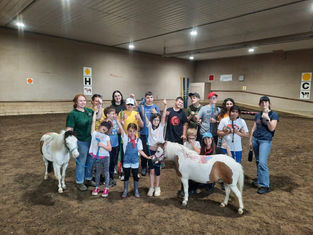Group of Children from a summer camp cheering, with two miniature horses